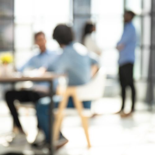 Foto unscharf mit zwei Personen am Tisch sitzend und zwei im Hintergrund stehend.