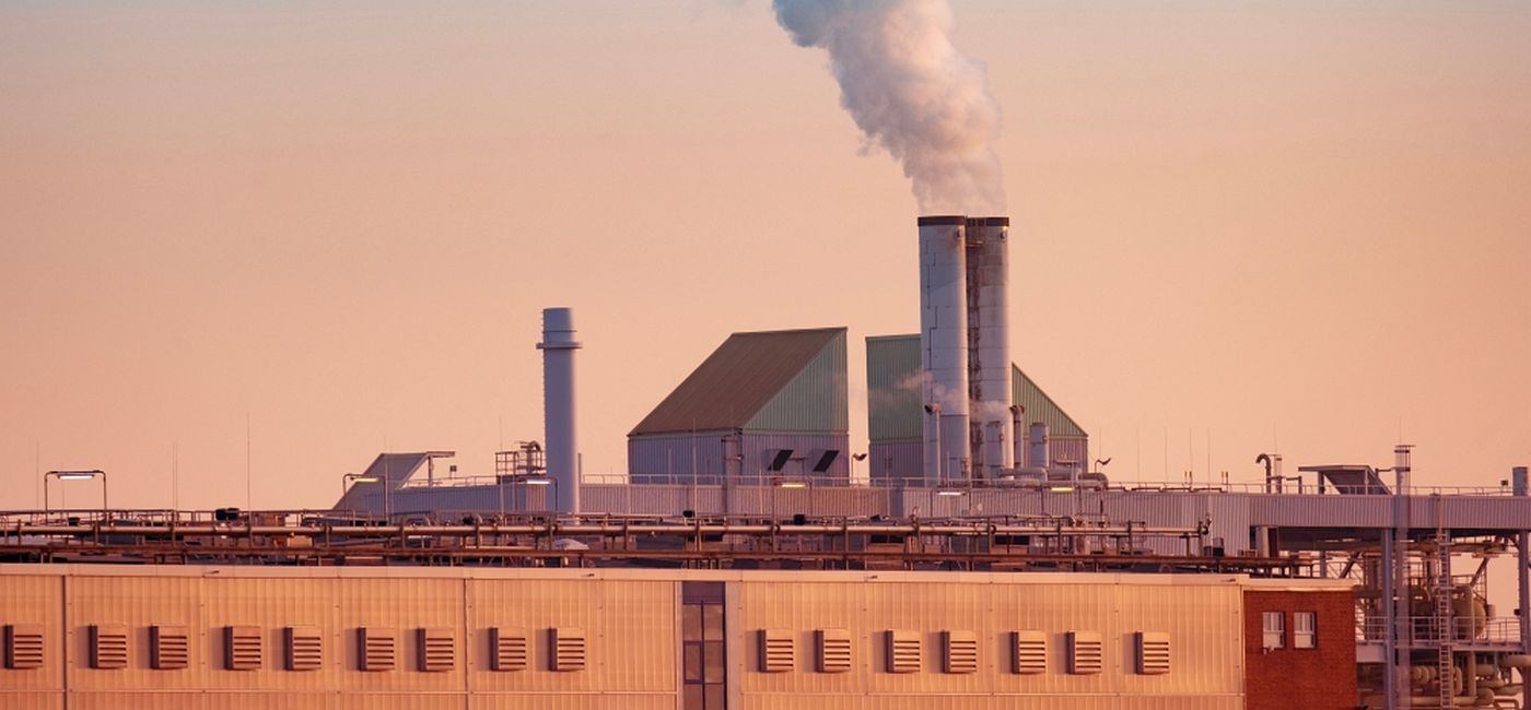 Moodbild Fabrik, aus deren Schornstein Dampf in den Himmel des Sonnenuntergangs aufsteigt, symbolisiert den FutureCamp Artikel zum nEHS-Auktionshandel 2026